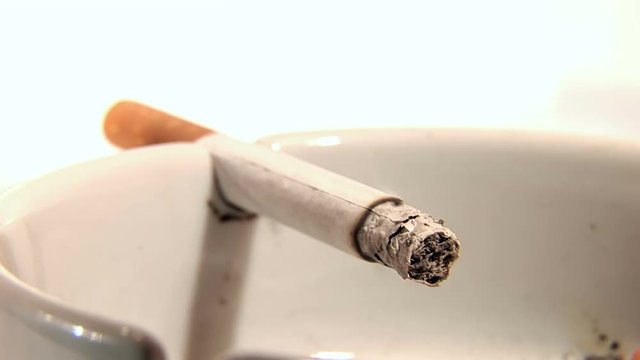Cigarette burning in a filthy ashtray time lapse 
