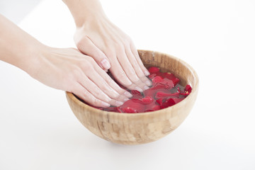 Obraz na płótnie Canvas Hands Spa.Manicure concept. Woman hands with wooden bowl of water with red roses petals