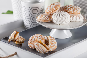 Sweet cookies on white tray with cups of coffee