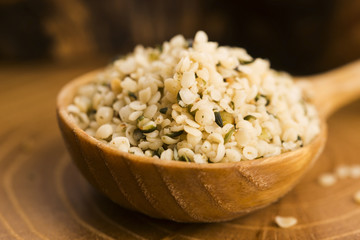 Shelled hemp seeds on wood background