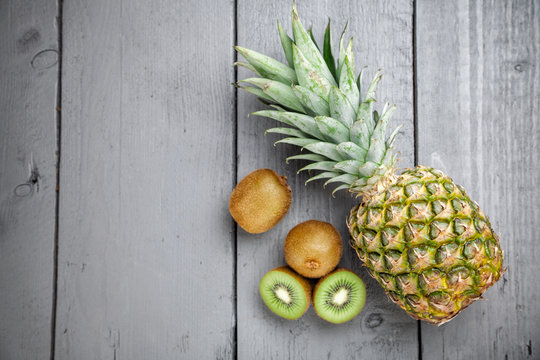 Delicious kiwi and pineapple fruit on grey wooden background