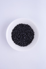 Black Soybeans in a white bowl isolated on white background.