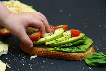Close up of toast with spinach leaves, avocado and tomatoes.