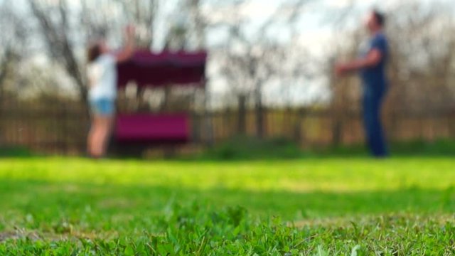 Father and daughter playing ball on backyard of a summer residence in the blurred background