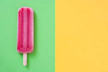 Strawberry popsicle on green and yellow background

