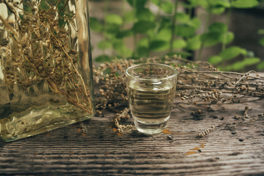 Wormwood drink in a small glass on rustic board