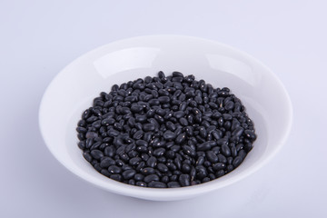 Black soybeans in white bowl on white background