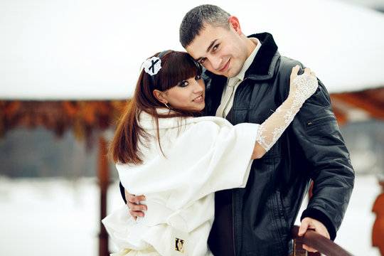 Newlyweds smile standing outside in winter weather