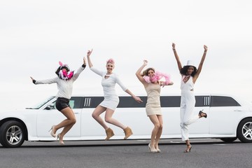 Happy friends jumping in front of a limousine - obrazy, fototapety, plakaty