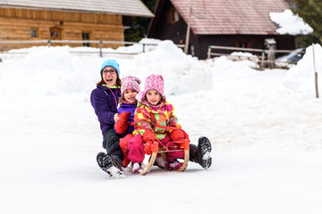 Family is sledding down the snowy slope