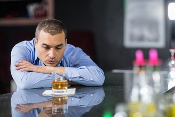 Depressed businessman looking at whisky glasses