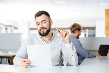 Happy businessman sitting on workplace and working with documents
