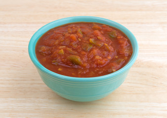 Bowl of chunky salsa sauce on table top side view