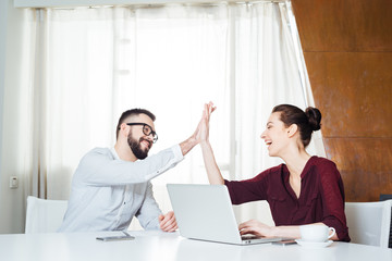 Two cheerful businesspeople celebrating success and giving high five