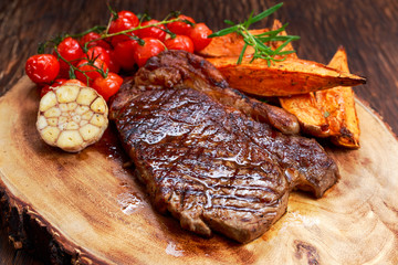 Grilled Beef Sirloin Steak on wooden board with vegetables.