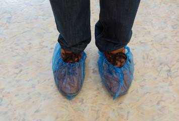 Blue medical shoe covers are worn over shoes