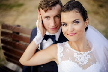 Newlyweds sitting at bench in park