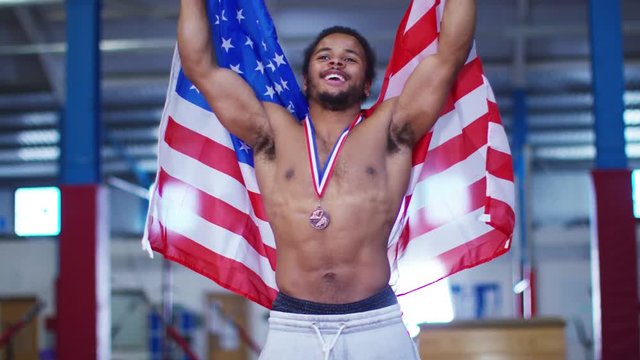 American gymnastics medal winner at competition, celebrating draped in flag