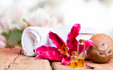 spa massage setting with lilium, oil, towel and salt on wooden background