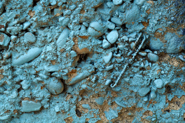 Dirty grey concrete wall with blue colored stones 10