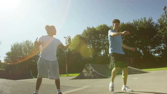  Happy young male friends, hanging out & dancing at skate park 