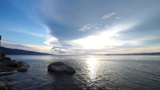 the sunrise through the rocks on the background water and sky panorama