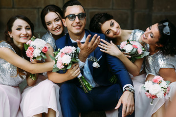 Charming bridesmaids are embracing young groom