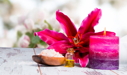 spa massage setting with lilium, oil, towel and salt on wooden background
