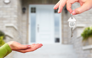 Hand with a key over new house background.