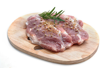 Raw pork meat on cutting board with herbs isolated on white