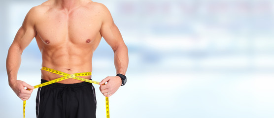 Man abdomen with measuring tape over blue background.