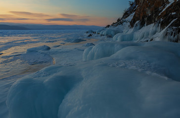 Huge icicles near rocks at sunrise.