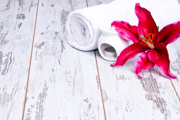 spa massage setting with lilium, oil, towel and salt on wooden background