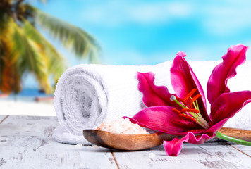 spa massage setting with lilium, oil, towel and salt on wooden background