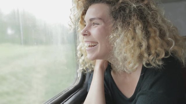 Smiling woman trip in train and looking at window