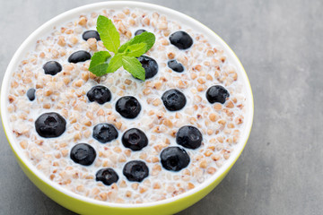 Buckwheat porridge in a bowl with mint leaves and blueberries.