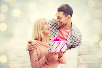 happy man giving woman present over holiday lights