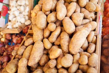 Fototapeta na wymiar Close Up of Brown Russet Baking Potatoes Piled in Crates at Food Market with Other Produce in Background