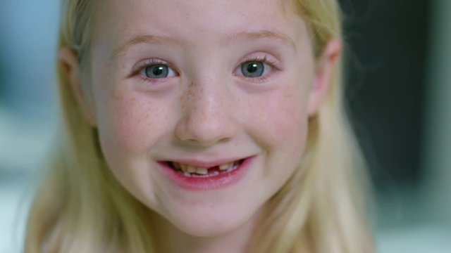  Close up portrait of little girl opening her mouth to show where she has lost one of her baby teeth. 