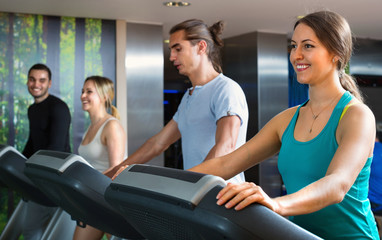 Group of  people doing cardio on treadmills in fitness club