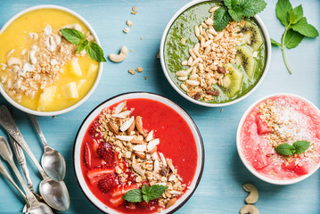 Healthy summer breakfast concept. Colorful fruit smoothie bowls on turquoise blue background