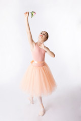 Fototapeta na wymiar Ballerina is dancing in a peach colour dress on a white background