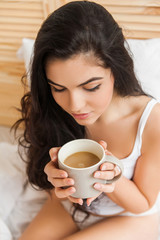 Beautiful woman drinking a coffee in her bed, topview