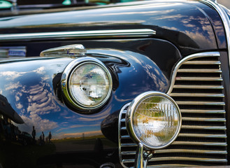 Close-up fragment of a black vintage car. Retro car. Headlights of vintage car. Selective focus.