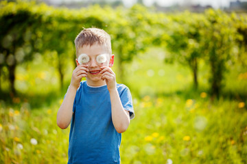 Child with white blowing dandeion eyes, on green background in a