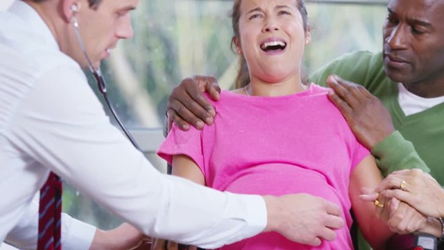  Pregnant woman going into labour is supported by her partner and medical staf