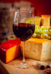Cheese and wine on a dark table.