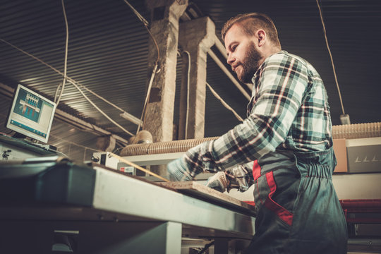 Carpenter works on wood plank in carpentry workshop.