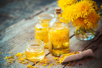 Bottles of dandelion tincture or oil, flower bunch, wooden scoop