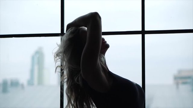 Blonde woman in bodysuit with perfect body standing in studio with sexy buttocks